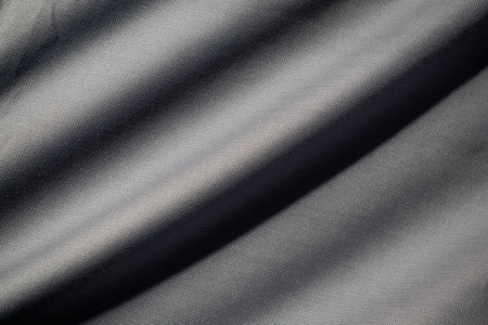 Wavy dark grey fabric background texture. shiny, glossy and elegant background.の写真素材