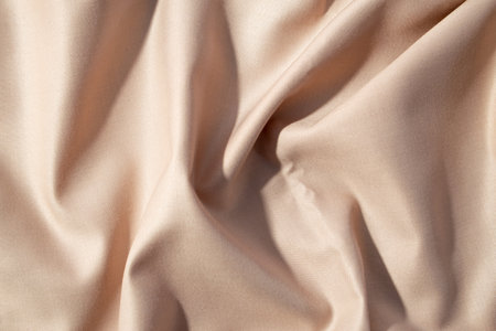 Close up silk shiny light brown fabric background texture.の写真素材