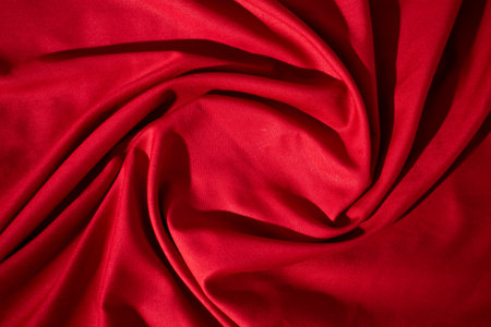 Red fabric wavy spiral crumpled background texture with copy space.の写真素材