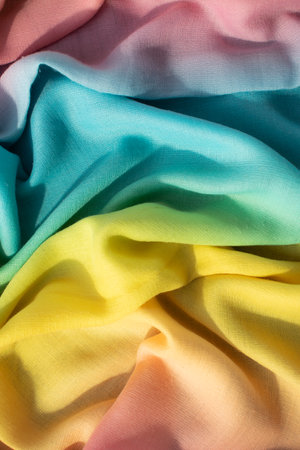 Gradient yellow blue pink and green fabric wavy crumpled background texture.の写真素材