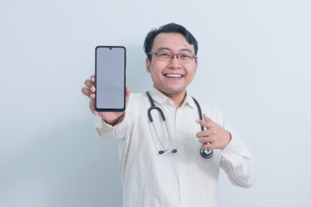 happy Asian man doctor, male nurse Pointing and showing phone isolated white background.の写真素材