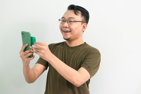 Asian man doing transaction with credit card and phone. Banking, Financial and technology isolated, green color concept.の写真素材