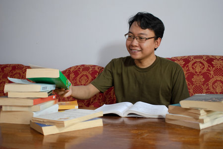 Asian student reading and writing on sofa at living room.の写真素材