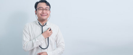 joyful Asian man doctor, male nurse using stethoscope to his chest body isolated white background.の写真素材
