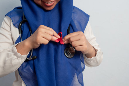 Close up Muslim Female Asian doctor or nurse wearing Red ribbons on cloth, HIV awareness concept, world AIDS day, world cancer day.の写真素材