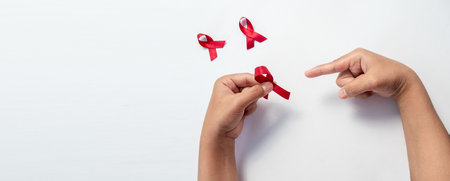 Female hand pointing red ribbon, HIV awareness concept, world AIDS day, world cancer day isolated white background.の写真素材