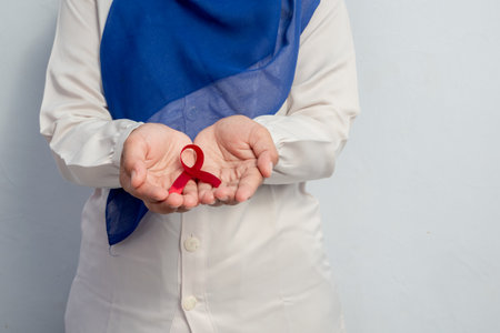 Happy Muslim Female Asian doctor or nurse holding Red ribbons, HIV awareness concept, world AIDS day, world cancer day with copy space over white background.の写真素材