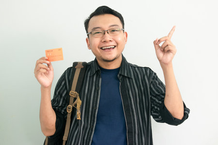 Happy asian student hold credit card with pointing gesture. Banking, Financial isolated concept.の写真素材