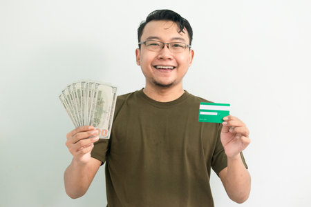 Happy asian man hold credit card and money. Banking, Financial isolated, green color concept.