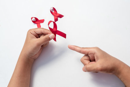 Female hand pointing red ribbon, HIV awareness concept, world AIDS day, world cancer day isolated white background.の写真素材