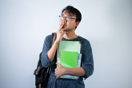 Asian young male with thinking gesture. Asian male with glasses wearing grey shirt with Isolated white backgroundの写真素材
