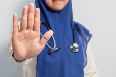 Joyful Muslim Female asian doctor or nurse with hand stop symbols pose. Isolated white background. Medical, healthcare and nurse concept.の写真素材