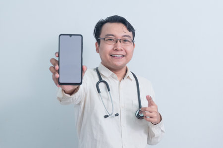 happy Asian man doctor, male nurse Pointing and showing phone isolated white background.の写真素材
