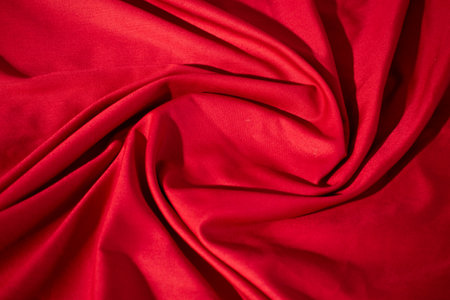 Red fabric wavy spiral crumpled background texture with copy space.の写真素材