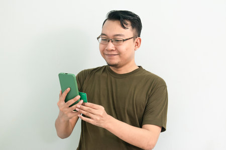 Asian man doing transaction with card and phone. Banking, Financial and technology isolated, green color concept.の写真素材
