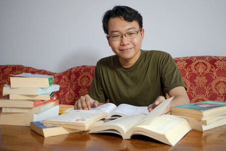 Asian young student study, reading and writing sit on sofa at living room.の写真素材