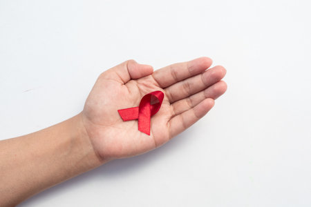 Female hand hold red ribbon, HIV awareness concept, world AIDS day, world cancer day isolated white...