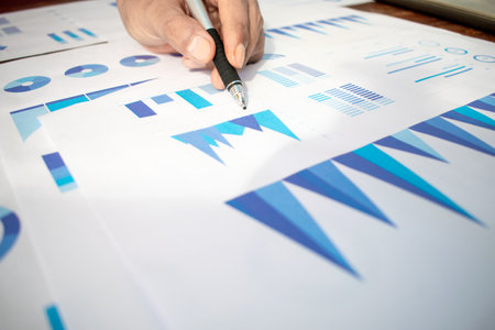 Close up businessman hand pointing graphic chart with pen. Financial, account, statistics and business data concept.の写真素材