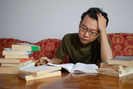 Asian young male reading book with frustrated gesture. Asian male with glasses confused face with isolated white backgroundの写真素材