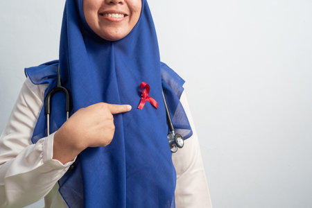 Happy Muslim Female Asian doctor or nurse pointing Red ribbons on cloth, HIV awareness concept, world AIDS day, world cancer day.の写真素材