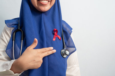 Happy Muslim Female Asian doctor or nurse pointing Red ribbons on cloth, HIV awareness concept, world AIDS day, world cancer day.の写真素材