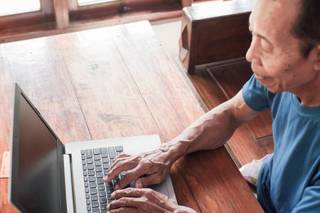 Asian old man with shirt using laptop in living room. Senior and technology conceptの写真素材