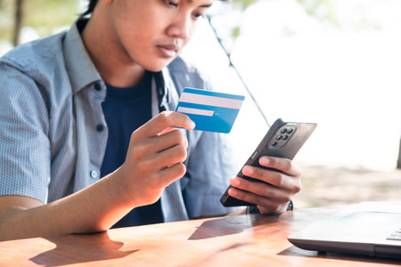 Happy Asian Young businessman hold blue creditcard and phone purchasing online shopping in outdoor...