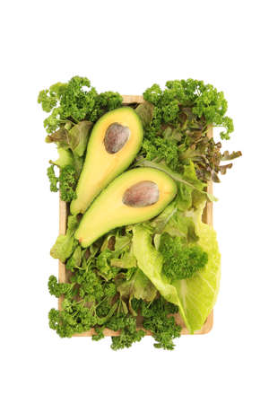 Mix of green salad and vegetable with avocado on wooden plate. Isolated on white.の写真素材