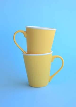 Two colorful yellow ceramic cups on light blue background.の写真素材