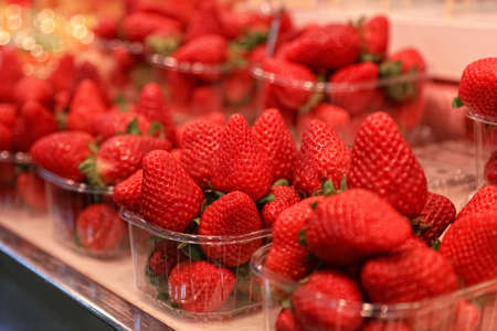 Red ripe sweet strawberries in plastic transparent containers at the market counterの写真素材