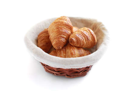 Five freshly baked tasty crusty croissants in wicker basket isolated on white.の写真素材