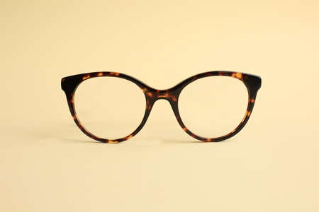 Modern fashionable acetate spectacles, torture color laying on light yellow background.の写真素材