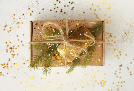 Christmas present. Craft paper box decorated with evergreen tree, golden card and cord.の写真素材