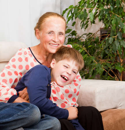 Laughing happy grandson hugs with grandmother