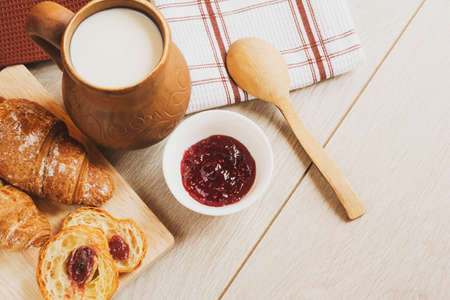 croissants, pitcher of milk strawberry jam on the table