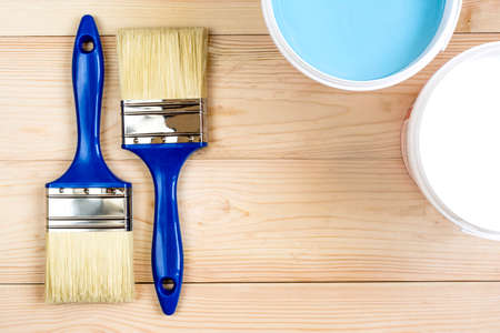 two brush and a white and blue paint on wooden boards in banks