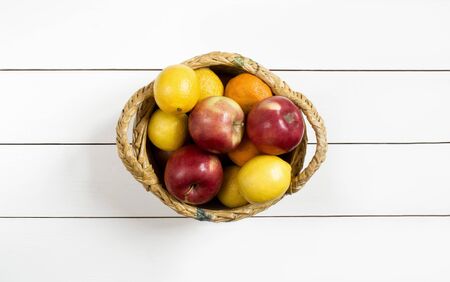 ripe fruits in a wicker basket on the white wooden table top viewの写真素材