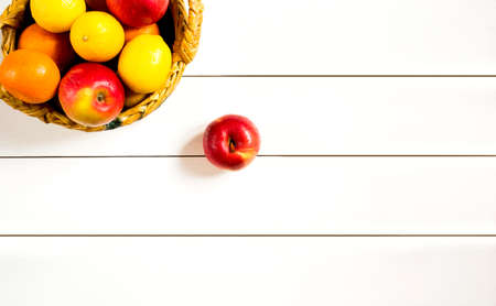 ripe fruits in a wicker basket on the white wooden table top viewの写真素材
