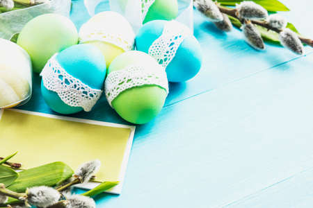 blue, yellow and green Easter eggs in blue lace on the table against the background of willowの写真素材