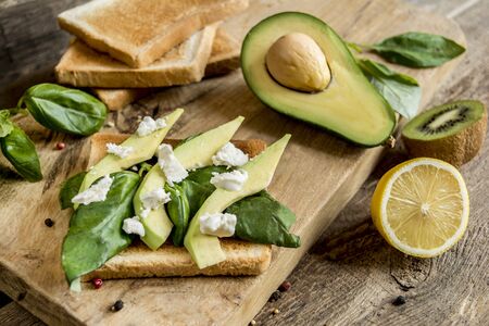 healthy sandwich with cheese and avocado on wood board on foliage background