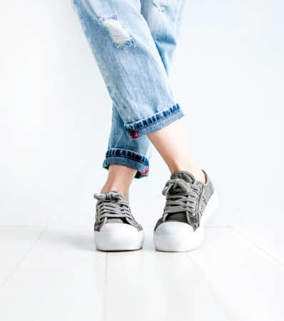 Female shoes sneakers legs in jeans on a white backgroundの写真素材