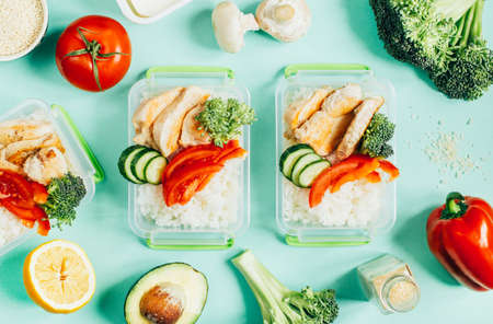 top view of vegetables, rice, meat in plastic bowls on light green backgroundの写真素材