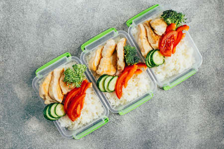 top view of vegetables, rice, meat in plastic bowls on light gray backgroundの写真素材