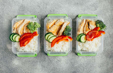 top view of vegetables, rice, meat in plastic bowls on light gray backgroundの写真素材
