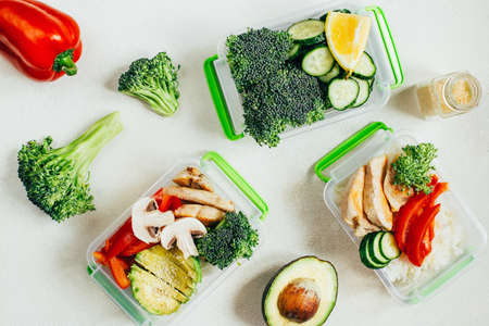 top view of vegetables, rice, meat in plastic bowls on light white backgroundの写真素材