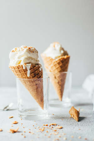 close-up of white vanilla ice cream in a waffle cup on a gray tableの写真素材
