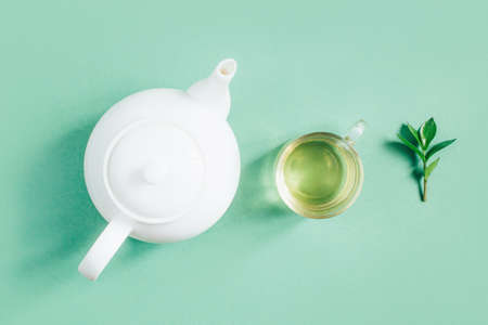 top view of a set of tea utensils teapot sugar bowl cup with tea on a green backgroundの写真素材