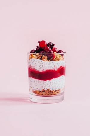 close-up of chia pudding with granola yogurt currants in a transparent glass on a pink backgroundの写真素材