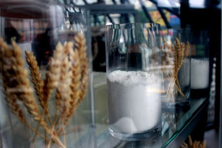 Ears of wheat and flour powder in transparent glasses on the show-case.の写真素材