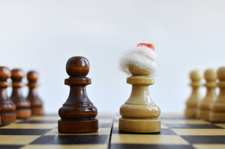 New Year on a chessboard, chess pieces in Santa's cap on a light backgroundの写真素材